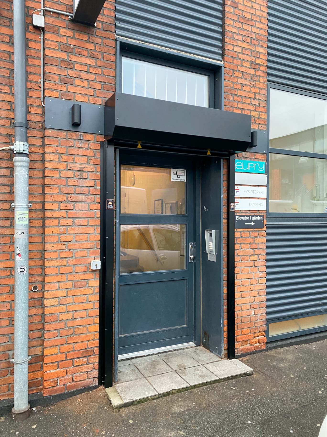 Sort rullegitter monteret over erhvervsindgang i murstensfacade